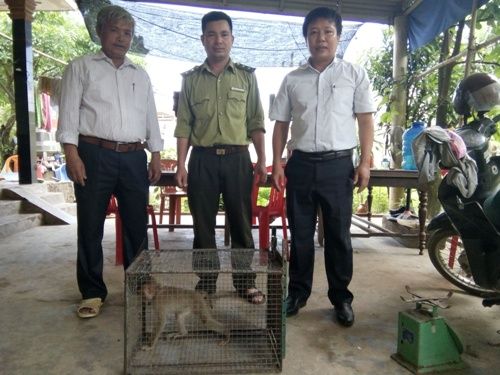 A group of men standing next to a cage with a monkey Description automatically generated