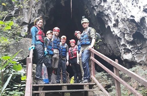 A group of people standing on a wooden bridge in a cave

Description automatically generated