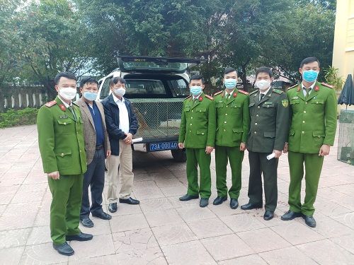 A group of men wearing masks and standing in front of a truck
Description automatically generated