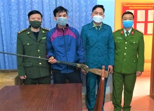 A group of men wearing face masks and holding a weapon Description automatically generated
