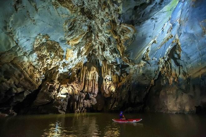 A person in a boat in a cave Description automatically generated