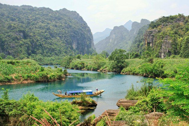 A boat on a river surrounded by trees and mountains Description automatically generated