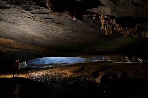 A cave with a light shining through Description automatically generated