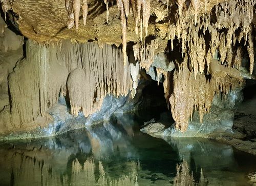 A cave with water and stalactites Description automatically generated