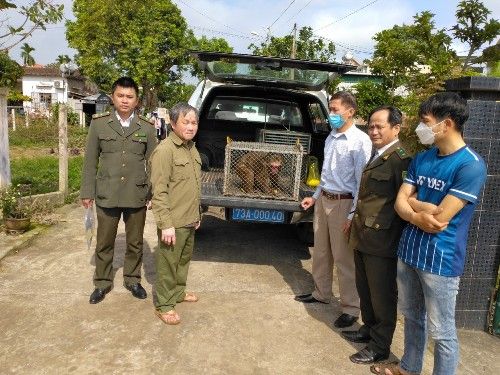 A group of men standing next to a car with a cage in the back

Description automatically generated