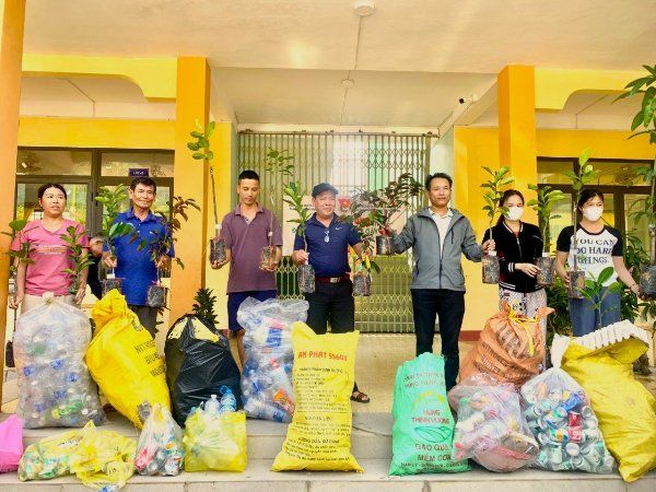 A group of people standing outside of a building with bags of trash Description automatically generated